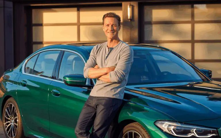 Ein zufriedener Mann steht vor seinem frisch aufbereiteten Auto