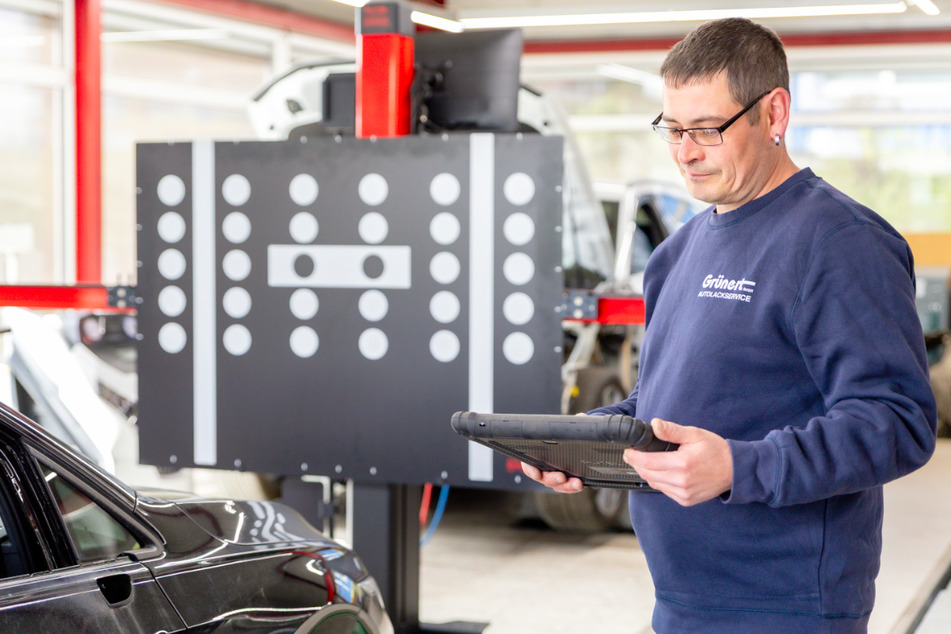 Ein Mitarbeiter kalibriert die Fahrerassistenzsysteme eines reparierten Fahrzeugs nach einem Unfallschaden.